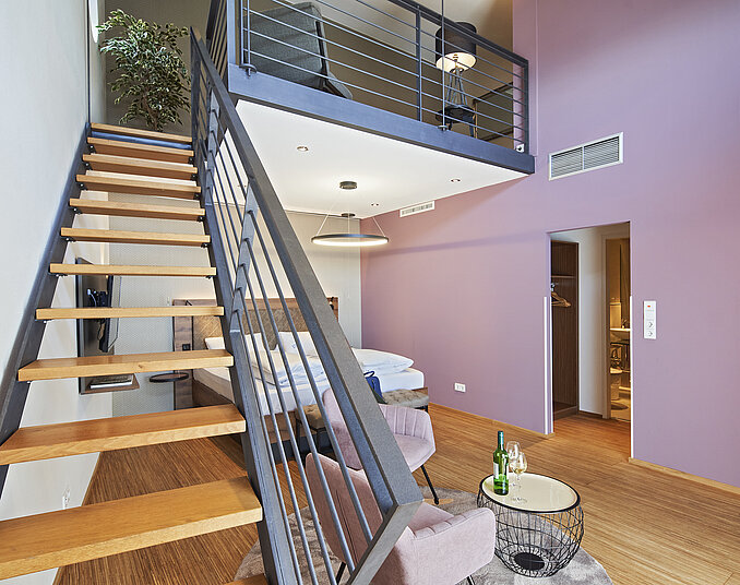 Maisonette-Hotelzimmer mit stilvoller Einrichtung, gemütlicher Sitzecke und offener Treppe im Hotel in Friedrichshafen.