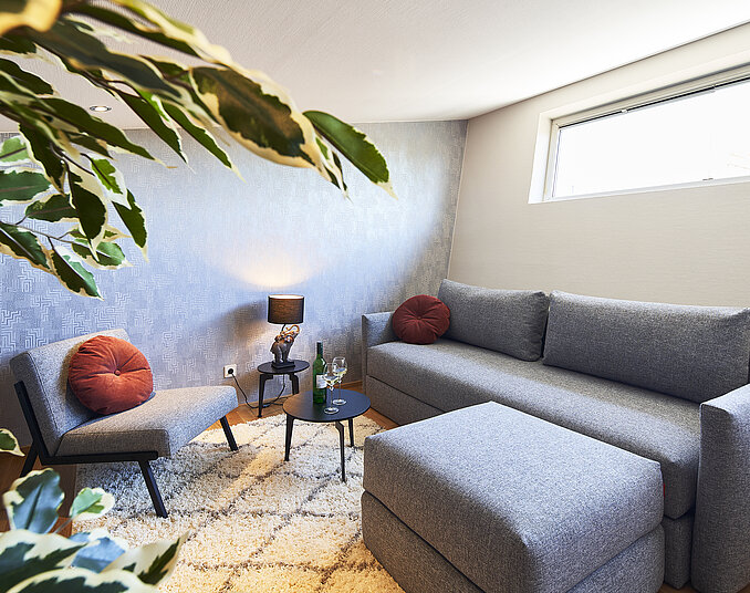 Gemütliche Sitzecke mit Sofa und Wein – stilvoll ausgestattete Hotelzimmer am Bodensee genießen.