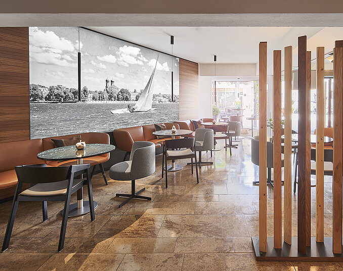 Modernes Café mit stilvollen Sitzmöbeln, warmem Ambiente und einer Wand mit einem Segelboot-Motiv.