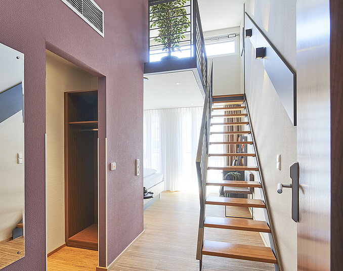 Helles Maisonette-Zimmer mit moderner Treppe – außergewöhnliche Hotelzimmer am Bodensee erleben.