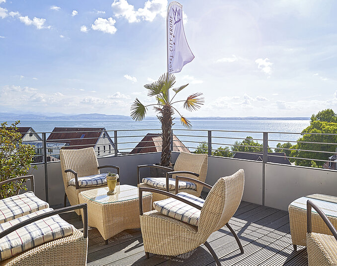 Sonnenterrasse mit Seeblick und Palmen – entspannter Genuss für Wellness in Friedrichshafen.