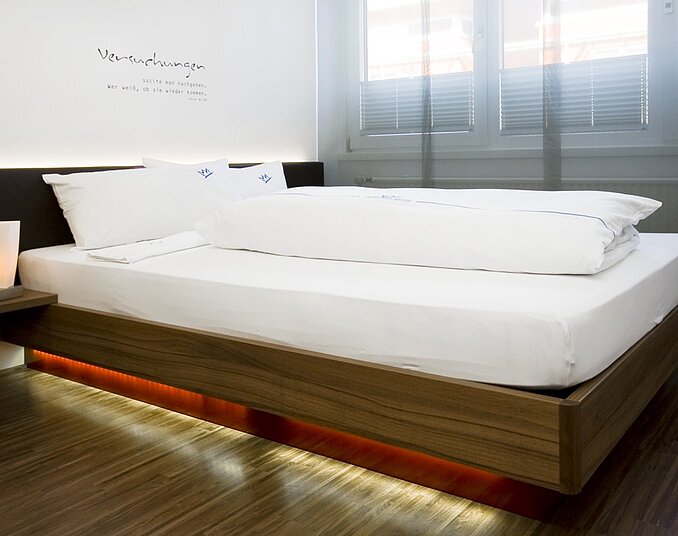 Modern and cozy double bed with ambient lighting – stylish hotelroom at Lake Constance.