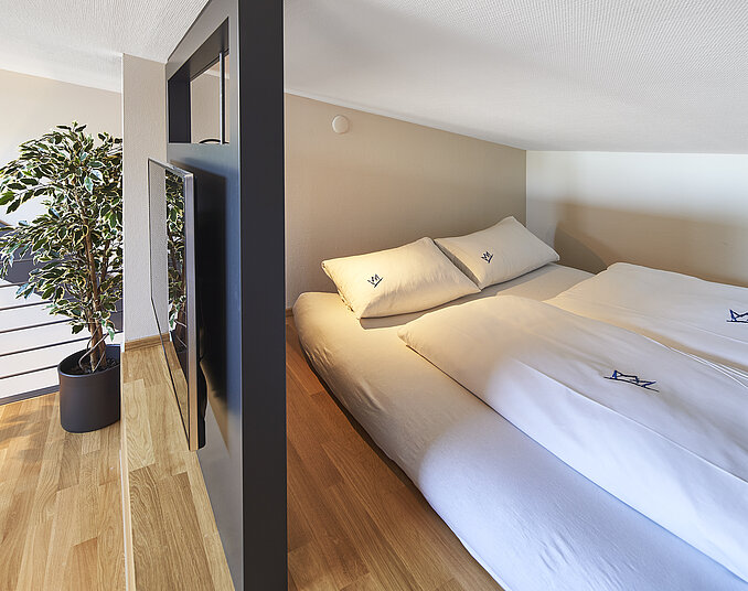Gemütliche Schlafnische mit Doppelbett und TV – außergewöhnliche Hotelzimmer am Bodensee erleben.