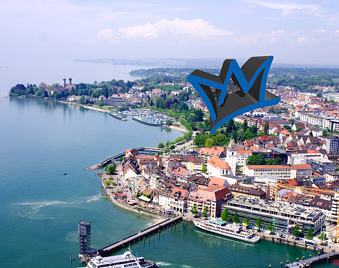 Luftaufnahme einer Stadt am Wasser mit einem Hafen und vielen Gebäuden, umgeben von grünen Anlagen. Im Vordergrund sind Boots- und Schiffsanlegestellen sichtbar. Ein großes stilisiertes Logo in Form einer Krone schwebt über der Stadt, was dem Bild eine moderne Note verleiht.